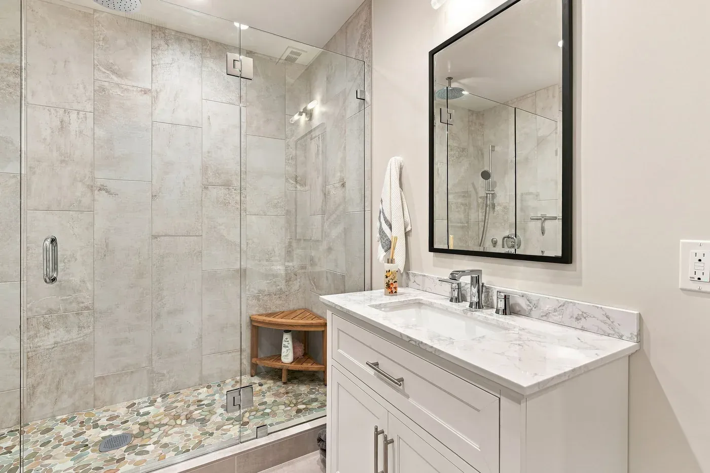 Bathroom with a frameless glass walk-in shower, large-format wall tile, and a river-pebble shower floor