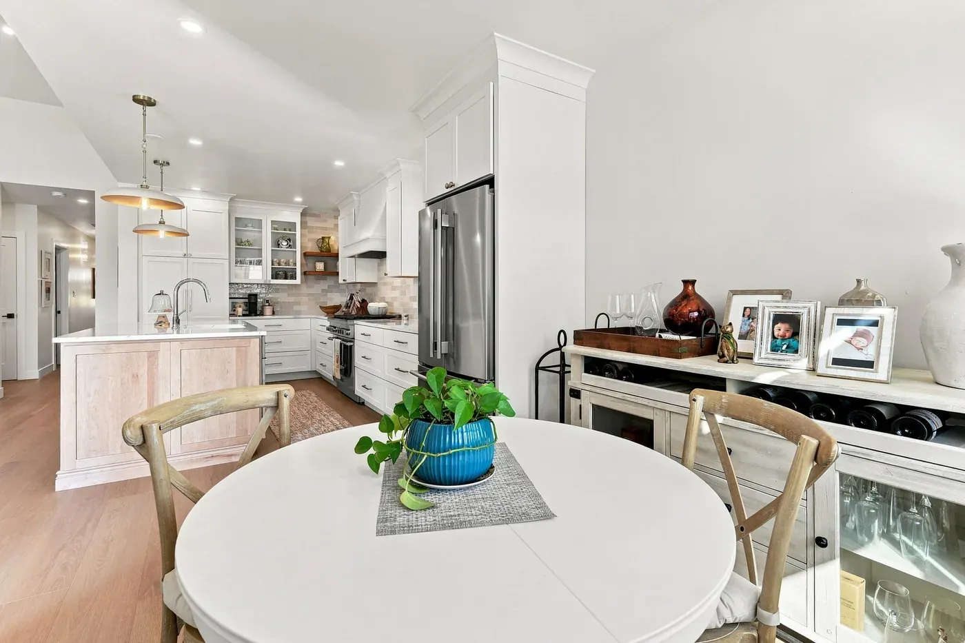 Breakfast nook with a round white table and cross-back chairs, looking into the kitchen