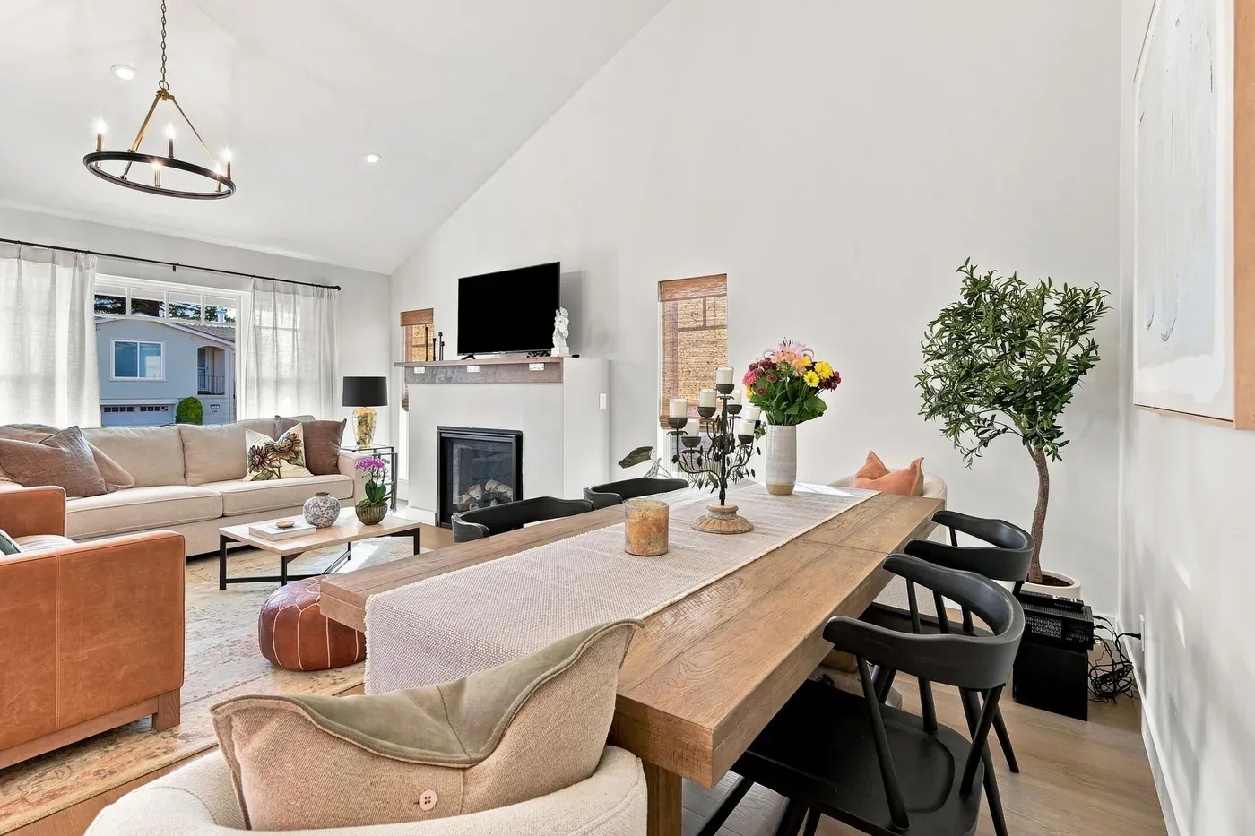 Dining table under the vaulted ceiling with the living room and fireplace beyond