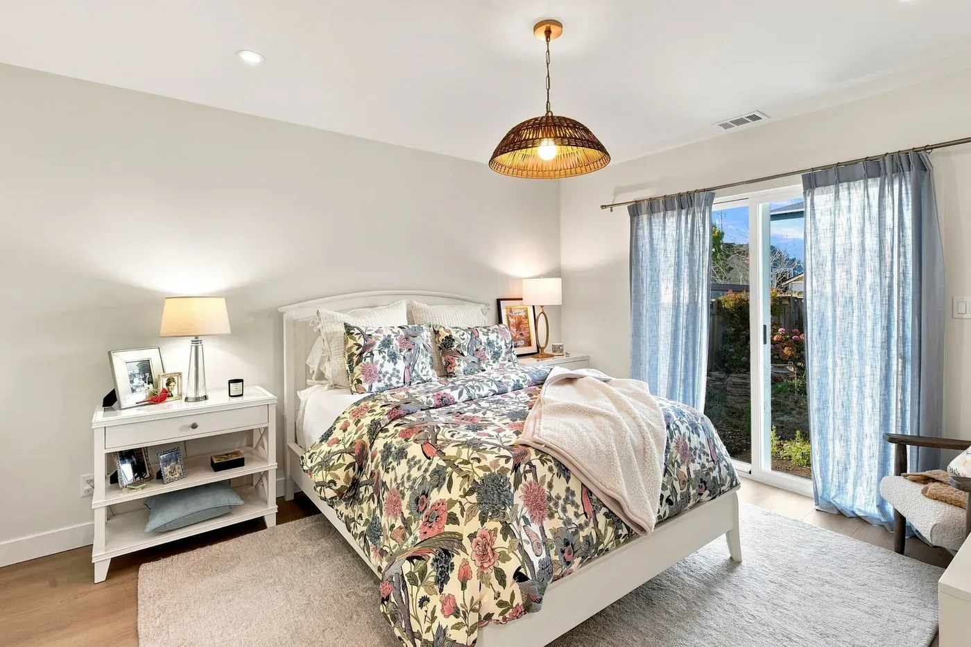 Bedroom with a woven pendant light and a sliding glass door hung with blue curtains
